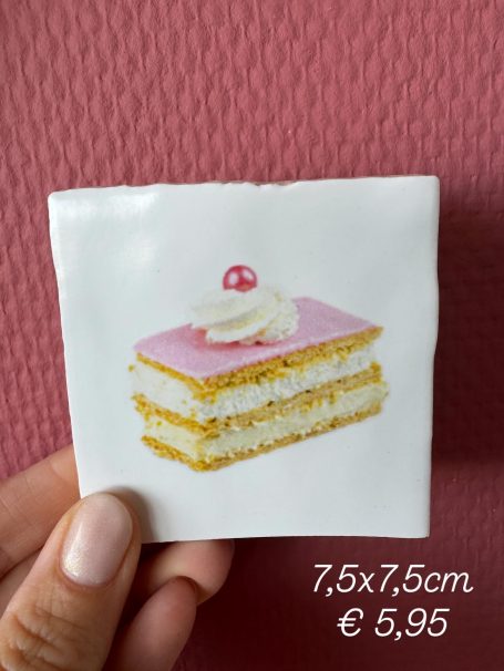 Een stuk gebak met roze glazuur, room en een kersenpresentatie op een witte achtergrond.